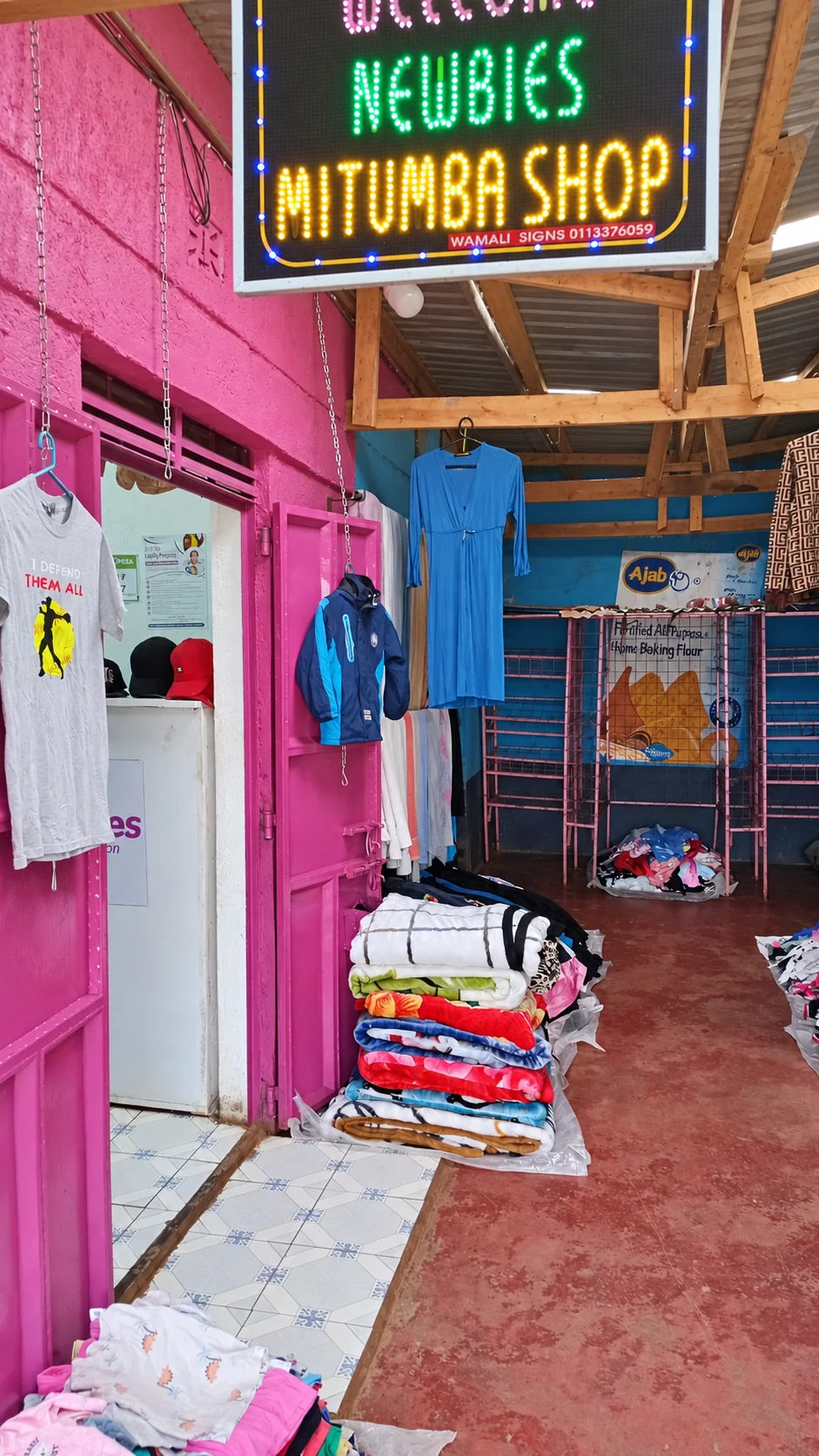 The entrance to Newbies, with its illuminated sign, pink doors and clothing displays